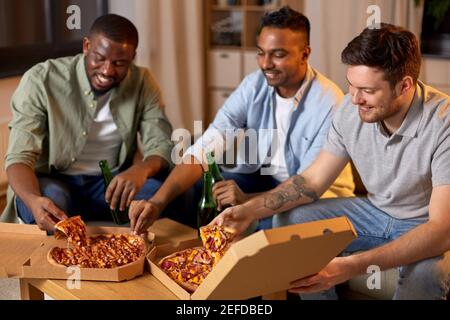 Glückliche männliche Freunde mit Bier essen Pizza zu Hause Stockfoto