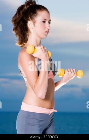 Seitenansicht einer jungen Frau, die das Training mit Hanteln Stockfoto