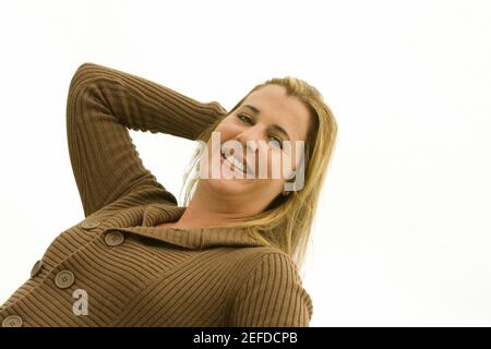 Porträt einer mittleren erwachsenen Frau, die mit ihrer Hand lächelt In ihren Haaren Stockfoto