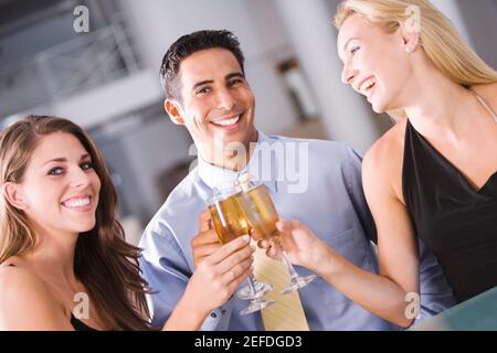 Porträt eines mittleren Erwachsenen Mann, der einen Toast mit Zwei junge Frauen Stockfoto