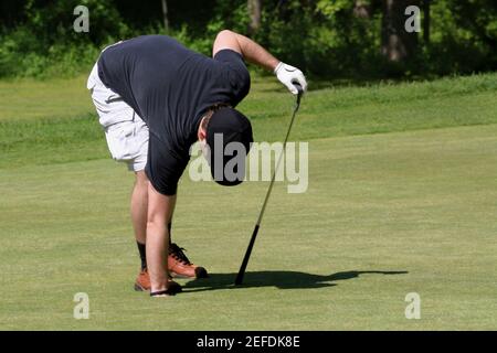 Mann, der seine Hand in ein Loch auf einem Golf legt Kurs Stockfoto