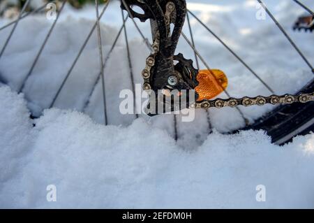 Hinterrad eines Fahrrads tief in weichen Schnee versenkt Mit dem orangefarbenen Reflektor und dem Schaltkettenventil Stockfoto