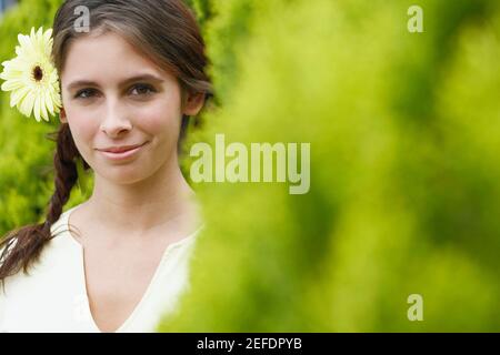 Porträt einer jungen Frau, die Blumen trägt Stockfoto