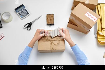 Hände, die Namensschild an Paketkasten bei der Post binden Stockfoto