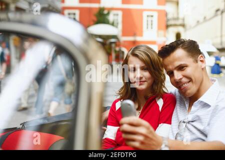 Ein Mann mittleren Erwachsenen und ein Mädchen im Teenageralter in einem Auto Halten eines Mobiltelefons Stockfoto