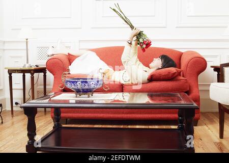 Seitenprofil einer jungen Frau, die auf einer Couch liegt Und hält einen Blumenstrauß Stockfoto