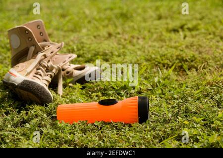 Nahaufnahme einer Taschenlampe in der Nähe eines Schuhs Auf dem Gras liegend Stockfoto