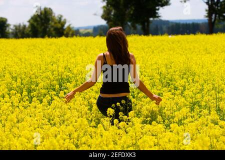 Rückansicht einer jungen Frau, die auf einem Feld läuft, Tschechische Republik Stockfoto