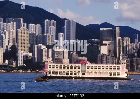 Fähre im Meer vor Wolkenkratzern, Hongkong, China Stockfoto