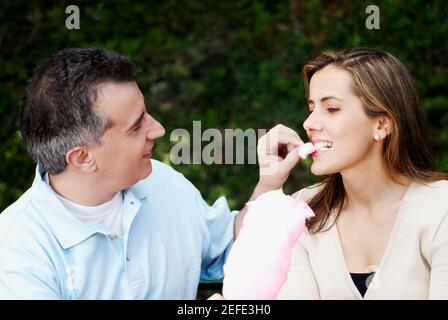 Nahaufnahme eines Mannes mit mittlerem Erwachsenen, der Zuckerwatte füttert Eine Frau mittleren Erwachsenen Stockfoto