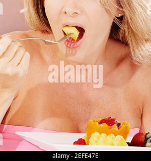 Nahaufnahme einer jungen Frau essen Obstsalat mit einem Gabel Stockfoto