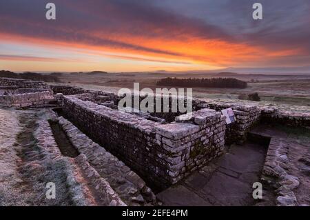 Ein herrlicher Sonnenaufgang am römischen Fort von Housesteads mit den Überresten der Latrinen, die auf dem Bild zu sehen sind - Hadrian's Wall, Northumberland, Großbritannien Stockfoto