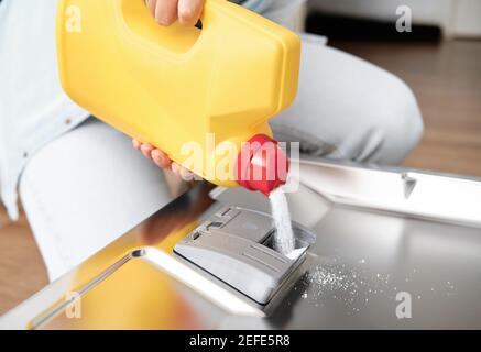 Frau gießt Pulver in die Geschirrspülbox. Geschirrspüler mit schmutzigen Schalen. Waschgerichte in der Küche Stockfoto