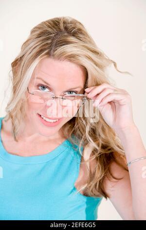 Porträt einer jungen Frau, die über ihre Brille guckend Stockfoto