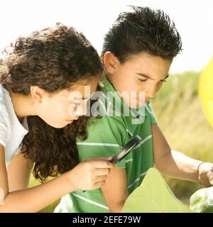 Nahaufnahme eines Jungen und eines Mädchens, die durch einen schauen Lupe Stockfoto