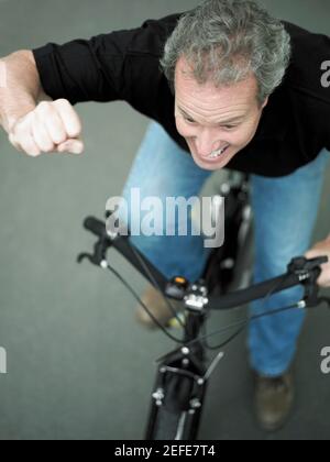 High-Angle-Ansicht eines reifen Mannes Radfahren mit seinem Hand angehoben Stockfoto