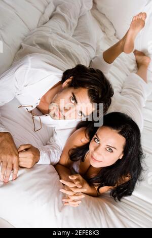 Porträt eines jungen Paares auf dem Bett liegend Stockfoto