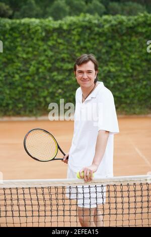 Portrait eines mittleren Erwachsenen, der zwei Tennisbälle hält Und einen Tennisschläger Stockfoto