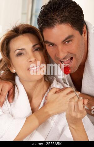 Porträt einer mittleren erwachsenen Frau, die einen mittleren Erwachsenen füttert Mann eine Erdbeere Stockfoto