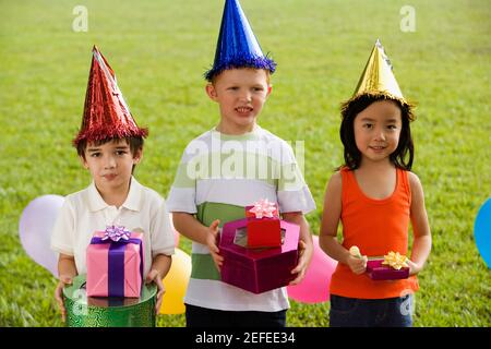 Drei Kinder stehen zusammen und halten Geschenke Stockfoto