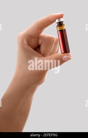Nahaufnahme einer personÅ½s Hand, die ein Fläschchen hält Stockfoto