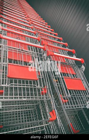 Shopping Metallic Wagen aufgereiht in Reihen im Shop Parkplatz. Supermarkt Gang mit leerem roten Warenkorb. Stockfoto