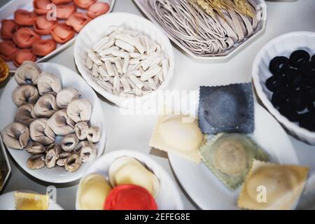 Nahaufnahme von ungekochten, sortierten Nudelgerichten und Knödeln in Tabletts Stockfoto