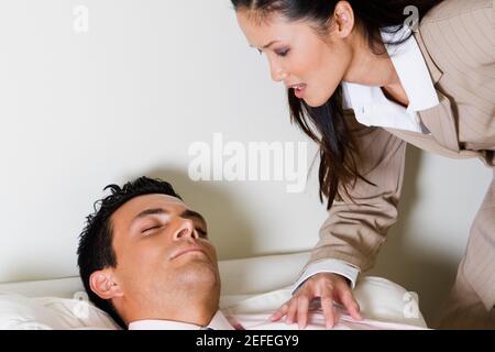 Geschäftsfrau, die sich über einen Geschäftsmann beugt, der auf einer Couch sitzt Stockfoto