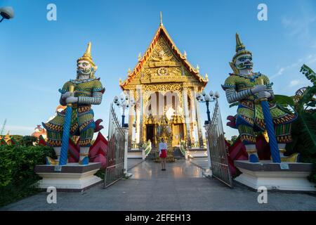 KOH SAMUI, THAILAND - 10. Januar 2020: Frau in einem roten Kleid steht vor der Festhalle am Wat Plai Laem Tempel. Stockfoto