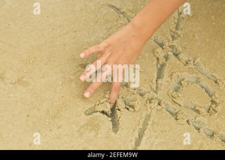 Nahaufnahme eines personÅ½s Hand spielenden Tic-tac-Toe im Sand Stockfoto