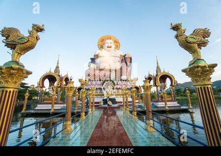 KOH SAMUI, THAILAND - 10. Januar 2020: Mann mit Kamera steht auf einer Brücke zu einer riesigen, farbenfrohen buddha-Statue am Wat Plai laem-Tempel auf koh samui Stockfoto