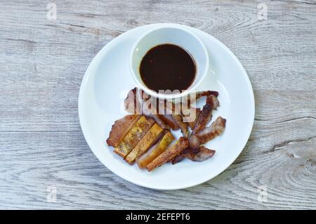 Gegrillte Schweinehals-Scheibe und in die Haut eintauchende würzige Sauce auf Platte Stockfoto