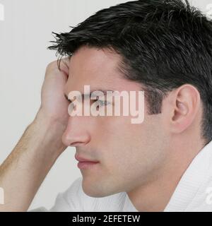 Seitenprofil eines jungen Mannes, der mit dem Kopf denkt In seiner Hand Stockfoto