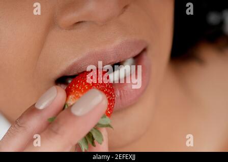 Nahaufnahme einer jungen Frau eine Erdbeere essen Stockfoto