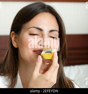 Nahaufnahme einer jungen Frau, die einen Cupcake riecht Stockfoto