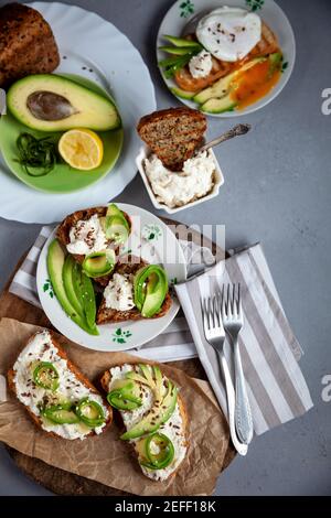 Sandwiches mit Weichkäse, Avocado und Gurke. Frühstück ist auf dem Tisch. Gesunde Ernährung. Toasten und darauf verteilen. Avocado Sandwich Stillleben Stockfoto