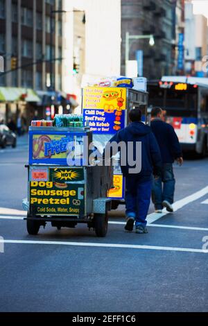 Zwei Männer, die einen Hot Dog Stand ziehen, Manhattan, New York City, New York State, USA Stockfoto