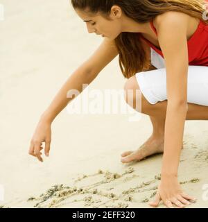 Seitenprofil eines Mädchens, das in Sand schreibt Stockfoto