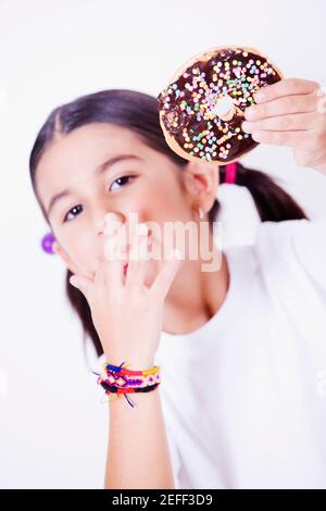 Portrait eines Mädchens, das einen Donut hält und sie leckt Finger Stockfoto