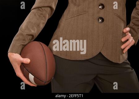 Nahaufnahme einer Geschäftsfrau, die einen amerikanischen Fußball hält Stockfoto