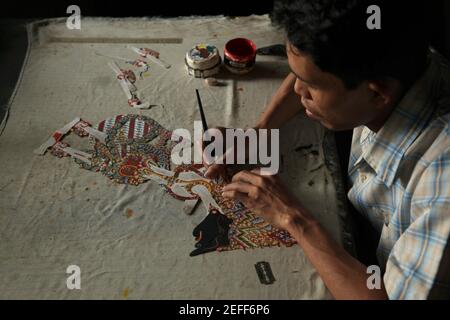 Handwerker färbt eine Wayang-Kulis-Puppe von König Kresna (Krishna) im Balai Agung-Handwerksladen in Surakarta, Zentraljava, Indonesien. Das traditionelle Puppenschattentheater Wayang kulit ist auf den Inseln Java und Bali in Indonesien weit verbreitet. Puppen für Wayang kulis sind aus Büffelleder gefertigt. Die Herstellung einer Puppe dauert etwa sechs Tage. Jeder Charakter hat seine eigenen Eigenschaften und kann leicht von den Zuschauern identifiziert werden. Stockfoto