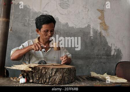 Handwerker macht eine Lederpuppe für wayang kulis Theater im klassischen Wayang Handwerksladen in Yogyakarta, Zentral Java, Indonesien. Das traditionelle Puppenschattentheater Wayang kulit ist auf den Inseln Java und Bali in Indonesien weit verbreitet. Puppen für Wayang kulis sind aus Büffelleder gefertigt. Die Herstellung einer Puppe dauert etwa sechs Tage. Jeder Charakter hat seine eigenen Eigenschaften und kann leicht von den Zuschauern identifiziert werden. Stockfoto