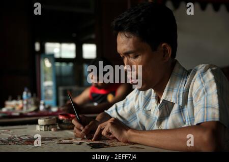 Handwerker färben wayang kulis Puppen im Balai Agung Handwerksladen in Surakarta, Zentraljava, Indonesien. Das traditionelle Puppenschattentheater Wayang kulit ist auf den Inseln Java und Bali in Indonesien weit verbreitet. Puppen für Wayang kulis sind aus Büffelleder gefertigt. Die Herstellung einer Puppe dauert etwa sechs Tage. Jeder Charakter hat seine eigenen Eigenschaften und kann leicht von den Zuschauern identifiziert werden. Stockfoto