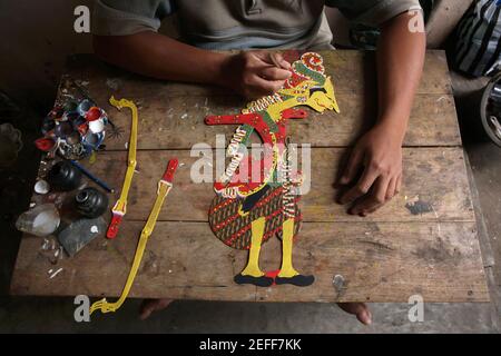 Handwerker färbt eine Wayang-Kulis-Puppe im klassischen Wayang-Handwerksladen in Yogyakarta, Zentral-Java, Indonesien. Das traditionelle Puppenschattentheater Wayang kulit ist auf den Inseln Java und Bali in Indonesien weit verbreitet. Puppen für Wayang kulis sind aus Büffelleder gefertigt. Die Herstellung einer Puppe dauert etwa sechs Tage. Jeder Charakter hat seine eigenen Eigenschaften und kann leicht von den Zuschauern identifiziert werden. Stockfoto