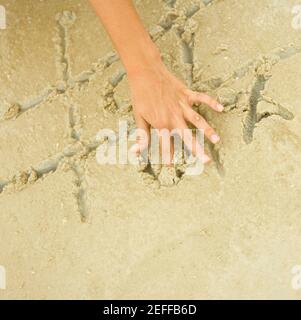 Nahaufnahme eines personÅ½s Hand spielenden Tic-tac-Toe im Sand Stockfoto