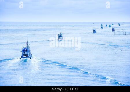 Viele Fischerboote fahren abends ins blaue Meer, viele traditionelle Fischerboote fahren in den Golf von Thailand in der Sommerdämmerung. Stockfoto