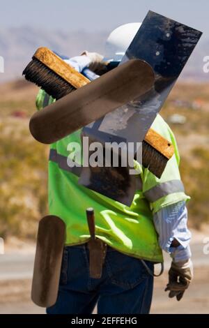 Rückansicht eines Bauarbeiters, der Handwerkzeuge trägt Seine Schulter Stockfoto