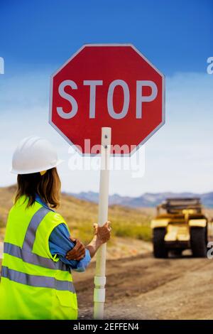 Rückansicht eines Mannes mit einem Stoppschild Eine unbefestigte Straße Stockfoto