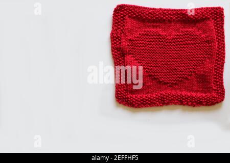 Rot gestricktes Quadrat mit Herzmotiv Stockfoto