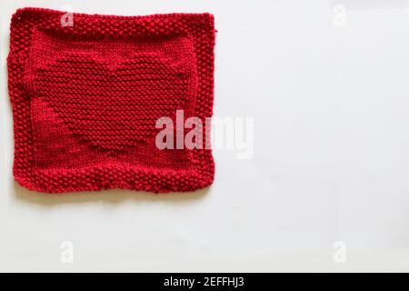 Rot gestricktes Quadrat mit Herzmotiv Stockfoto